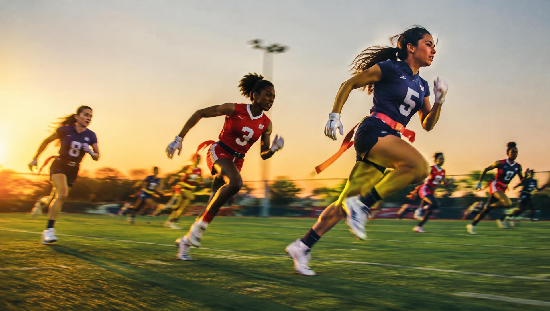 Young flag football players sprinting down the field at sunset